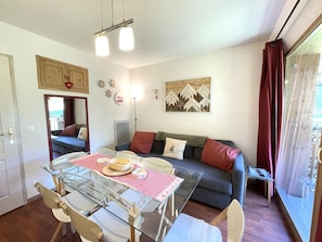 A compact living space with a dining table, sofa, and a large window. - Pleasant apartment, pets allowed - 6 guests (Valfréjus)