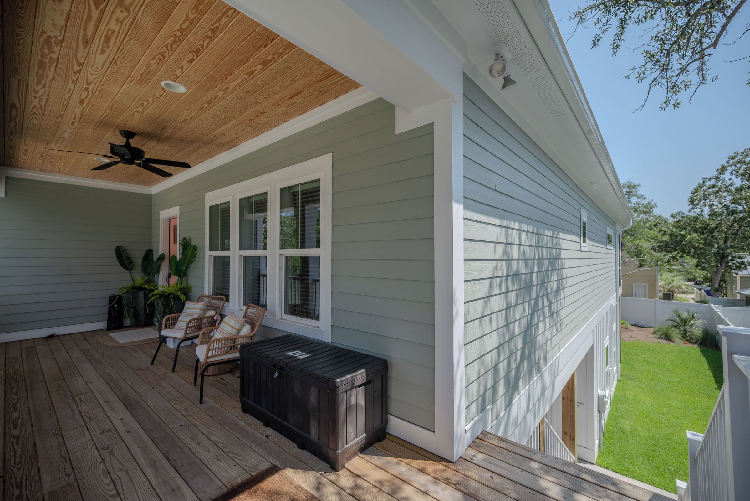 A covered patio with a ceiling fan, outdoor seating, and a grill.