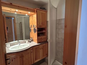 A bathroom with wooden cabinets, a sink, and a large mirror. - Bright apartment in the center, 6 guests (La Plagne Montchavin Les Coches)