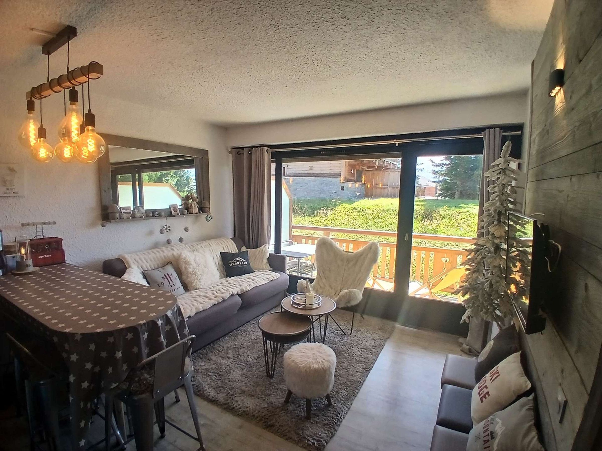 Un salon confortable avec un canapé, une table à manger et une vue sur un jardin, grâce à de grandes portes coulissantes.