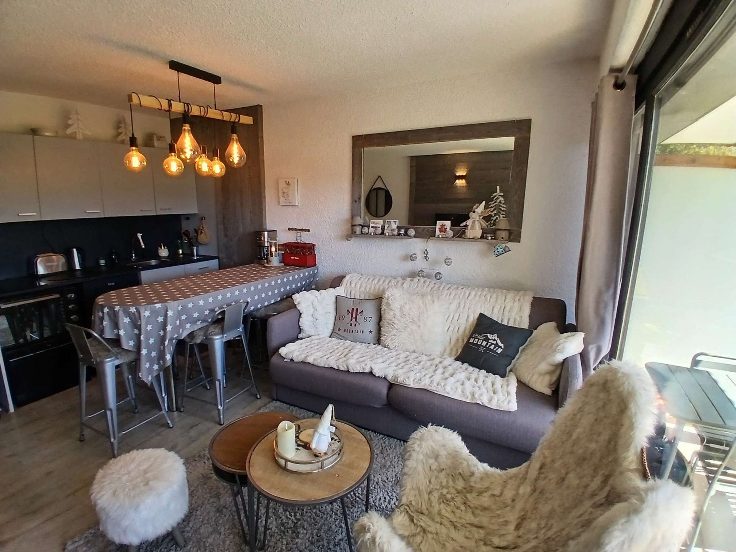A modern living room with a sofa, a dining table, and a kitchen area.