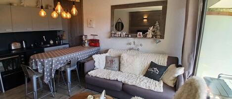 A modern living room with a sofa, a dining table, and a kitchen area.