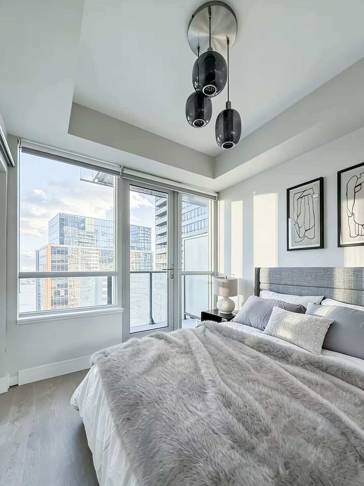 Une chambre moderne dotée d’un grand lit, offrant une vue sur la ville et présentant une décoration contemporaine.