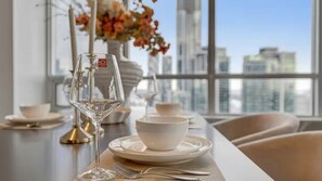 Mesa de jantar com vista clara para o horizonte urbano através de grandes janelas.