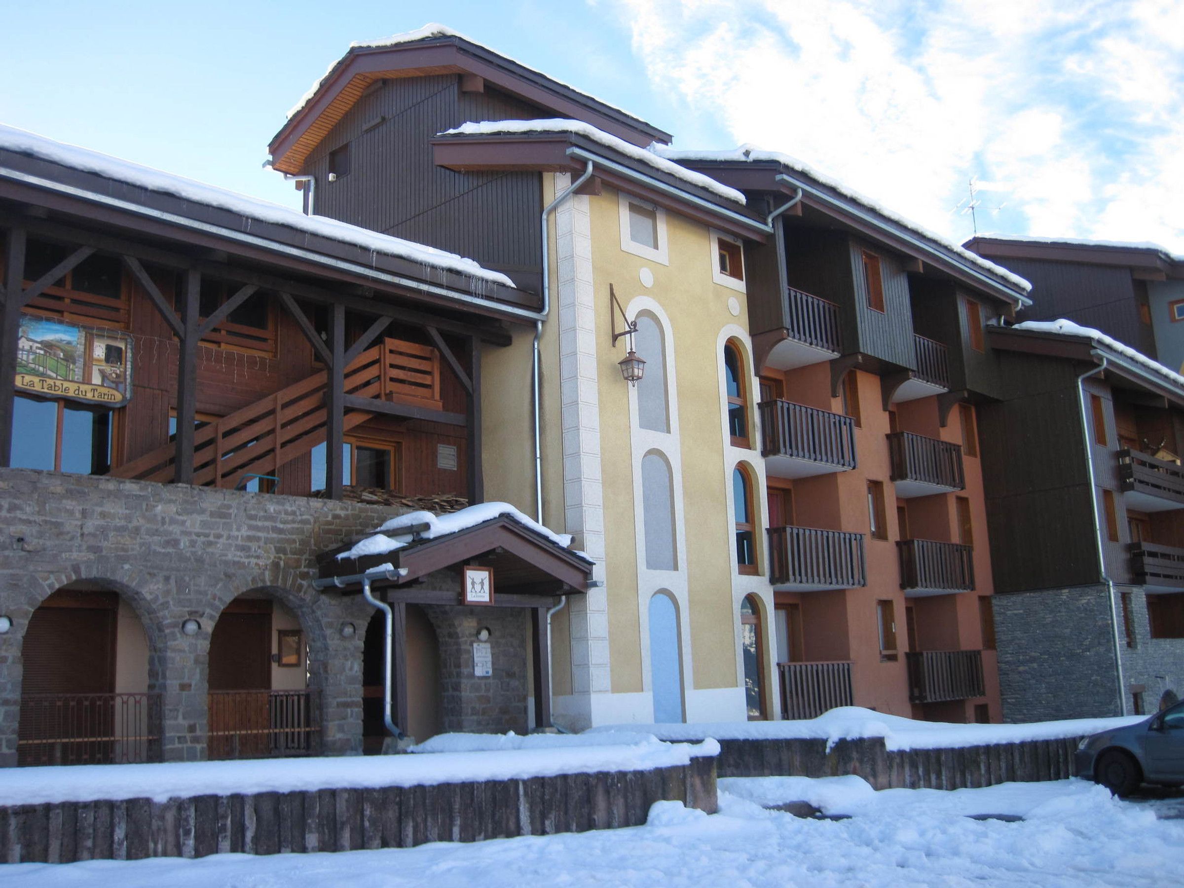 A multi-story building with a stone facade, wooden balconies, and a sign indicating a restaurant.