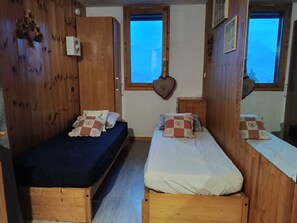 A room with two wooden beds, one with a blue mattress and the other with a white mattress. There are heart-shaped decorations on the walls and a window with a view. - Studio - 4 guests, Mont Blanc view (La Plagne Montchavin Les Coches)