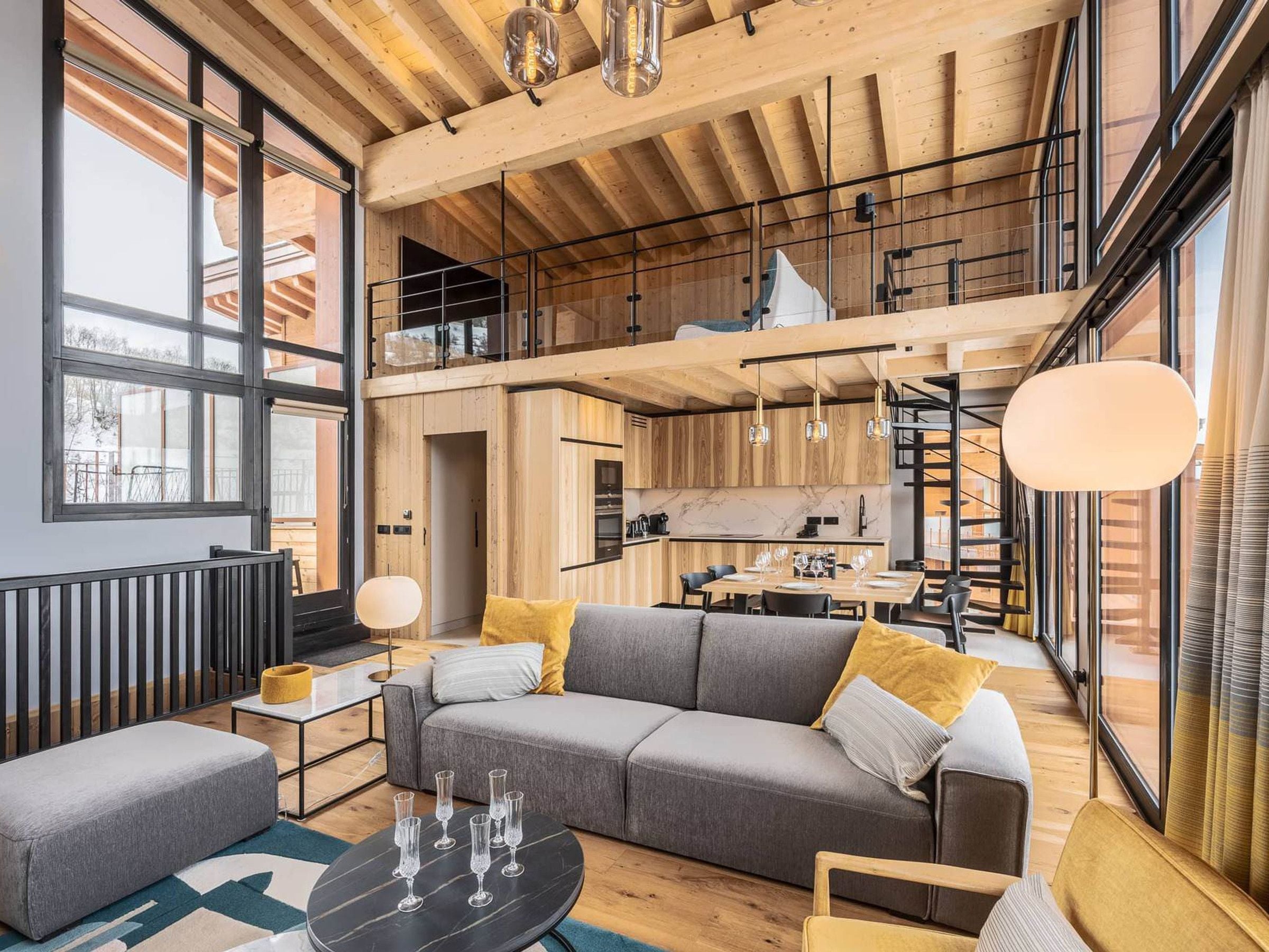 Ein moderner Loft-Wohnraum mit Essbereich, Küche und einer Treppe zu einer erhöhten Ebene.