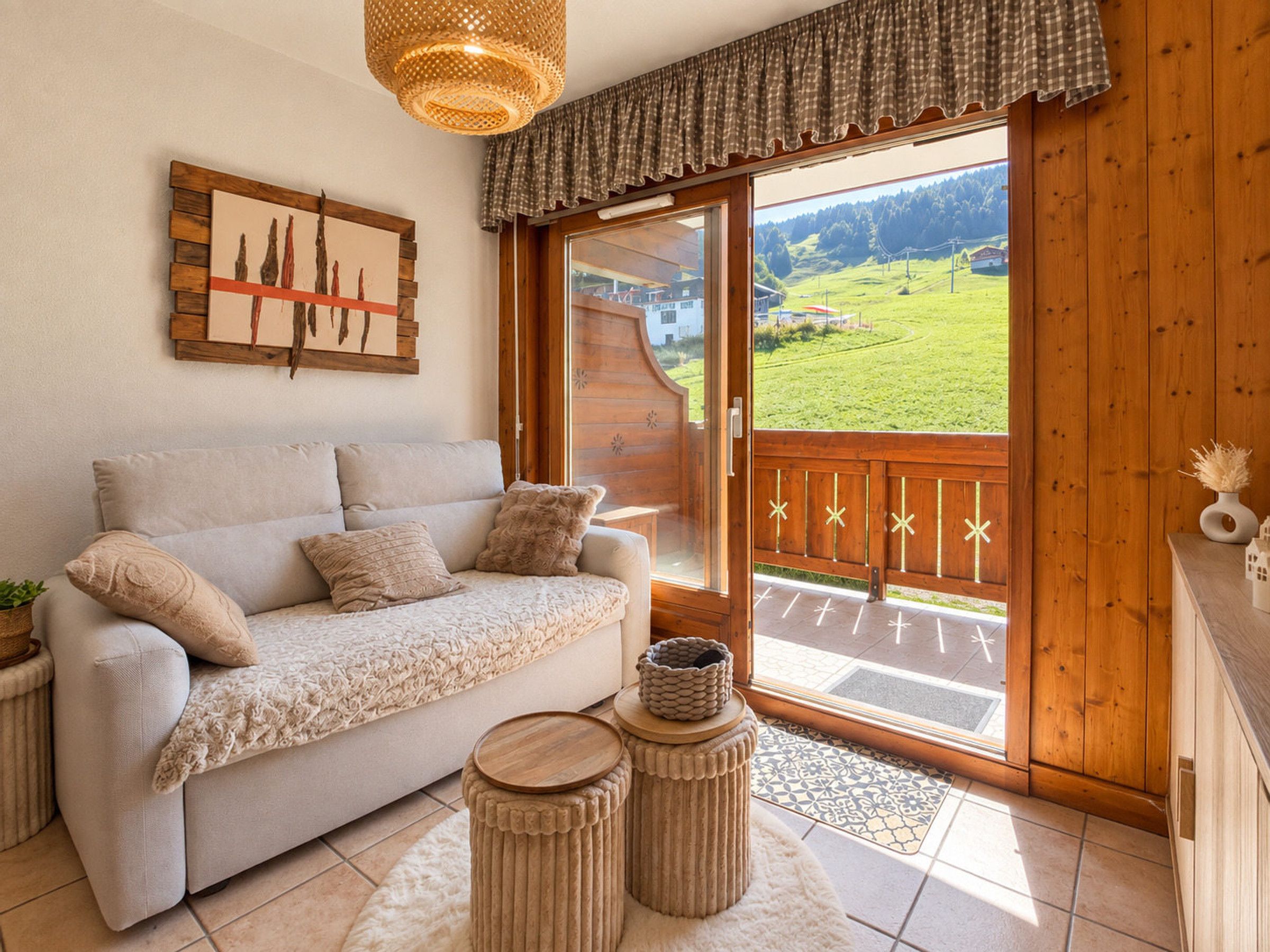 A cozy living room with a sofa, a decorative wall piece, and a view of a green landscape through a sliding glass door.