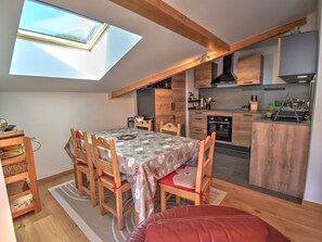Eine kompakte Küche mit Holzausbau, ein Essbereich mit Tisch und Stühlen sowie ein Oberlicht.