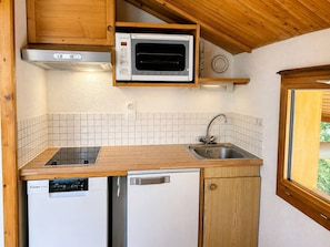 A compact kitchen with a microwave, dishwasher, and a window. - Quiet apartment near slopes - 4 guests (Les Allues)