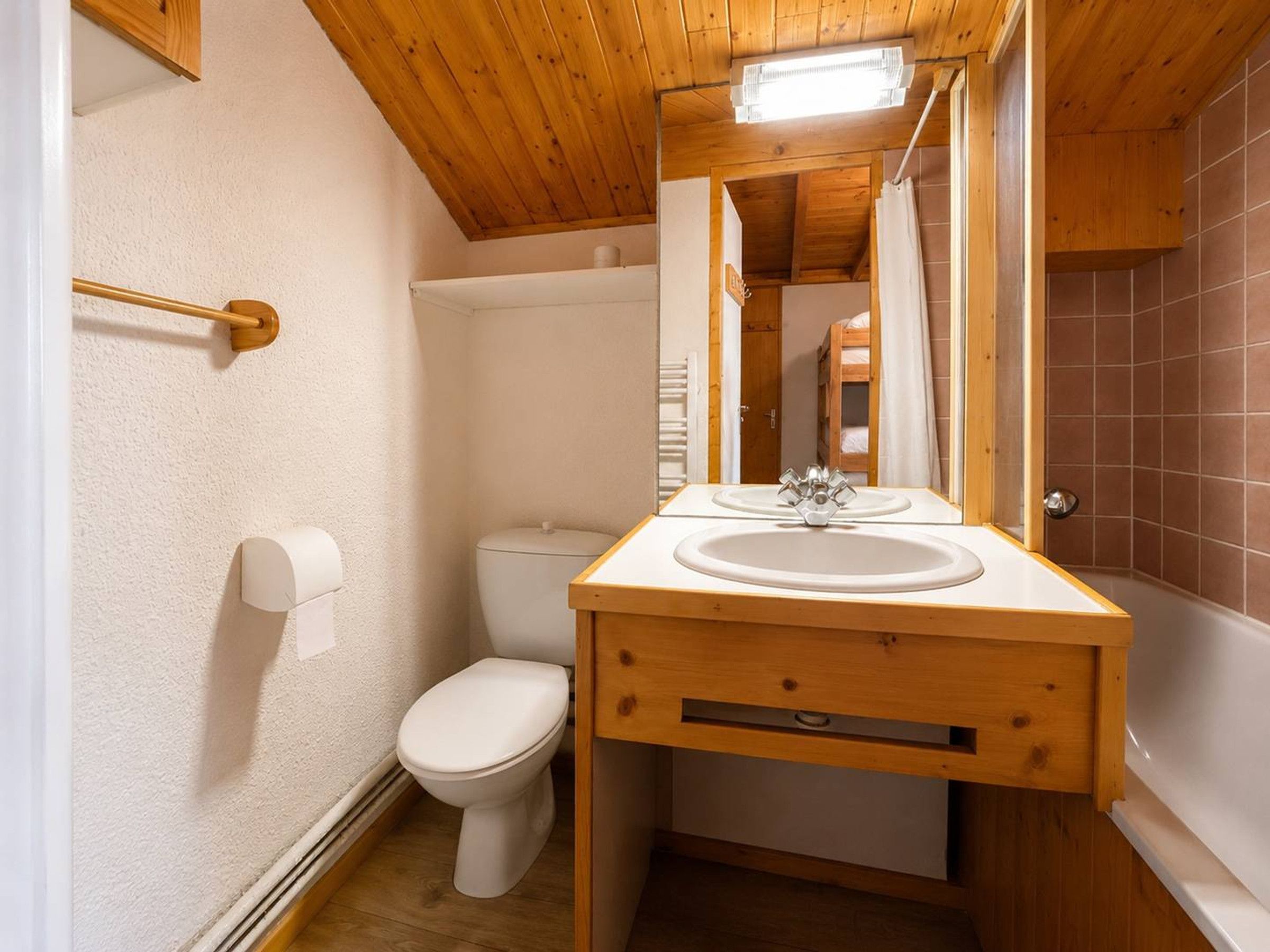 Ein kleines Badezimmer mit einem Holzkosmetikschrank, einer Toilette und einer Duschkabine.