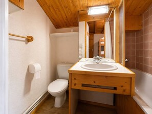 A compact bathroom with a wooden vanity, a toilet, and a shower area. - Quiet apartment near slopes - 4 guests (Les Allues)