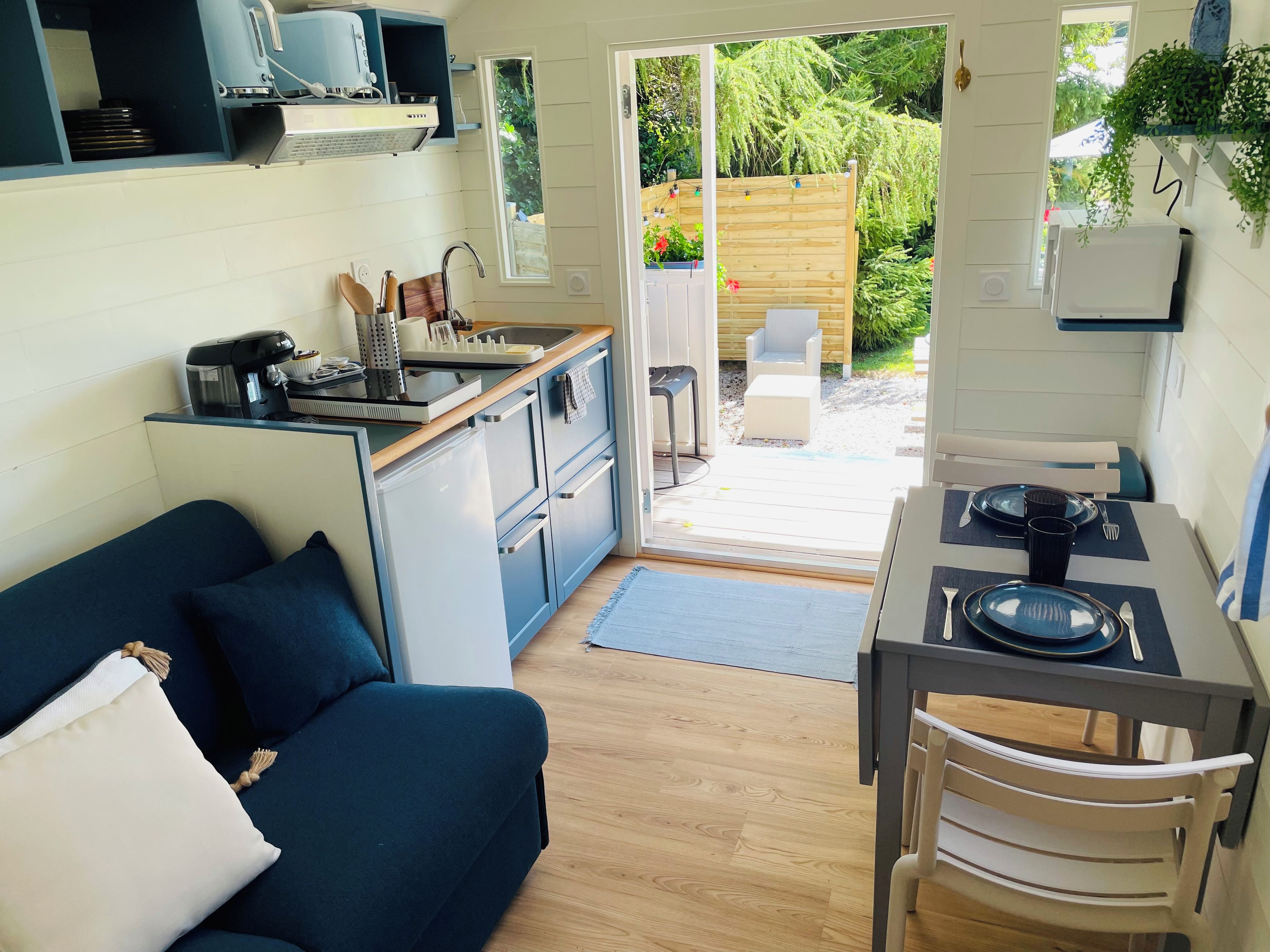 Une cuisine compacte avec un coin repas, un canapé et une vue sur le jardin.