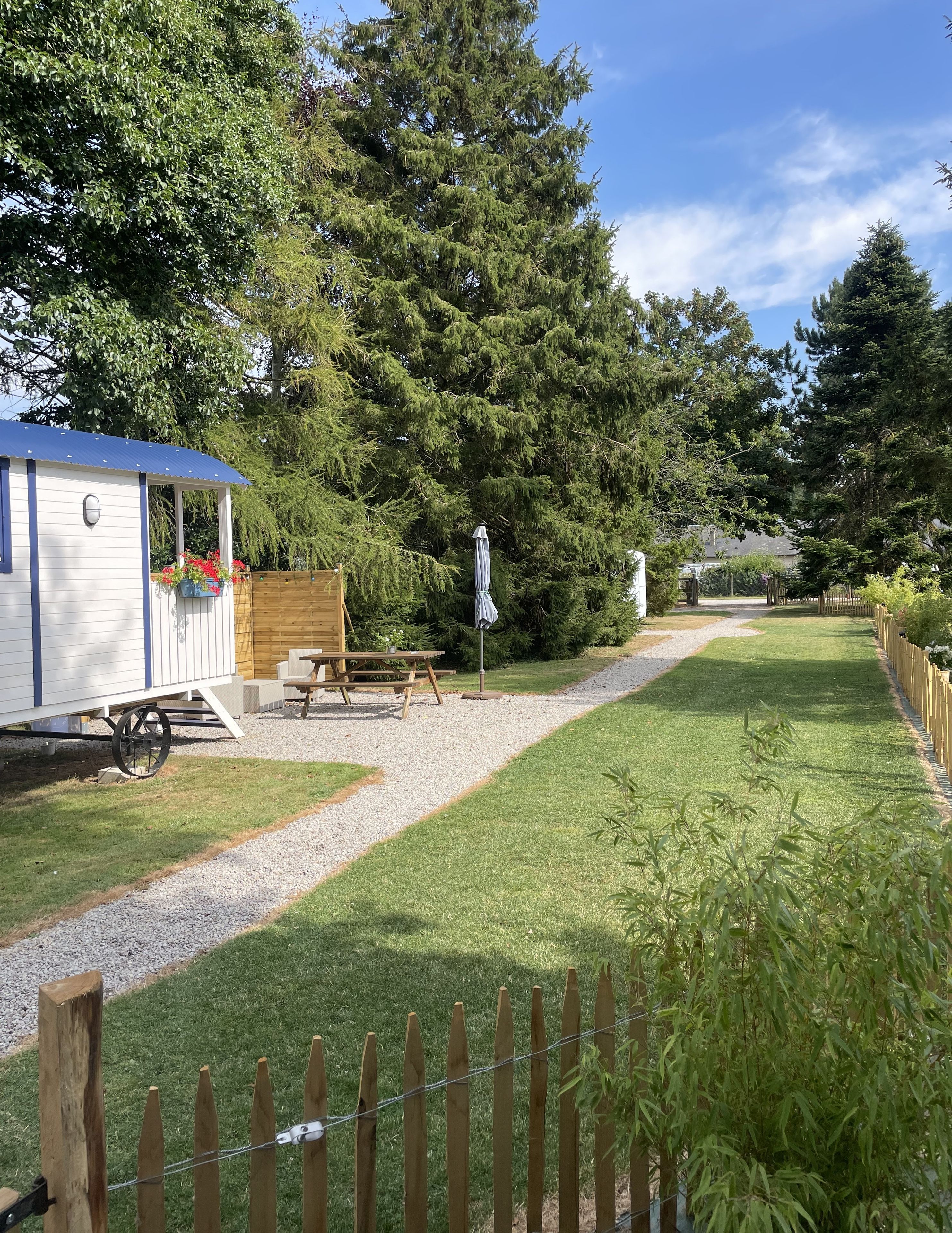 A campsite with a small cabin, picnic table, and umbrella.