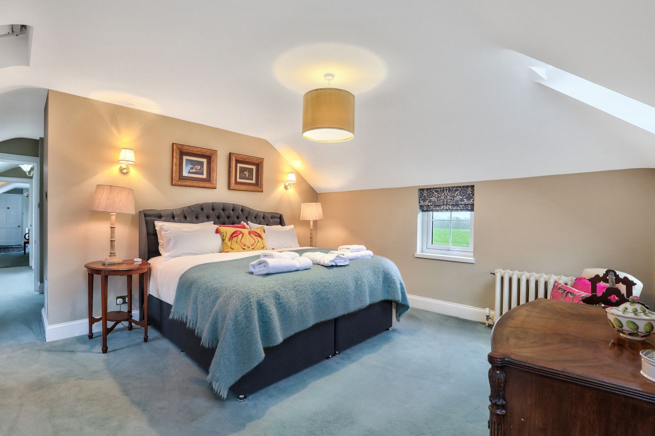 A bedroom with a large bed, bedside lamps, a window with a view, and a radiator.