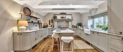 A modern kitchen with a central island, wooden flooring, and white cabinetry.