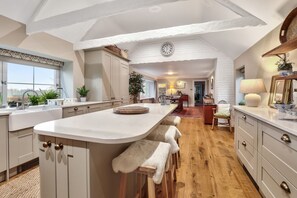 Een ruime keuken met een groot eiland, houten vloeren en uitzicht op de eethoek.