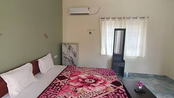 Un dormitorio con cama, mesita de noche, espejo y ventana con cortinas.