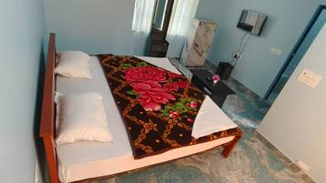 Un dormitorio con cama, almohadas, una colcha decorativa, una mesita de noche, un aparador y un televisor.