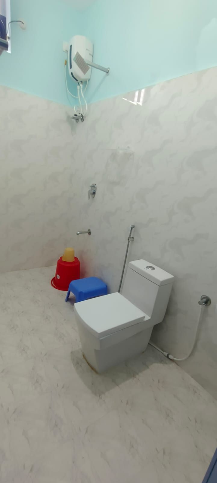 Un baño con inodoro, ducha y calentador de pared.