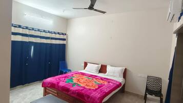 Une chambre à coucher avec un lit, une chaise, un ventilateur de plafond et un rideau.