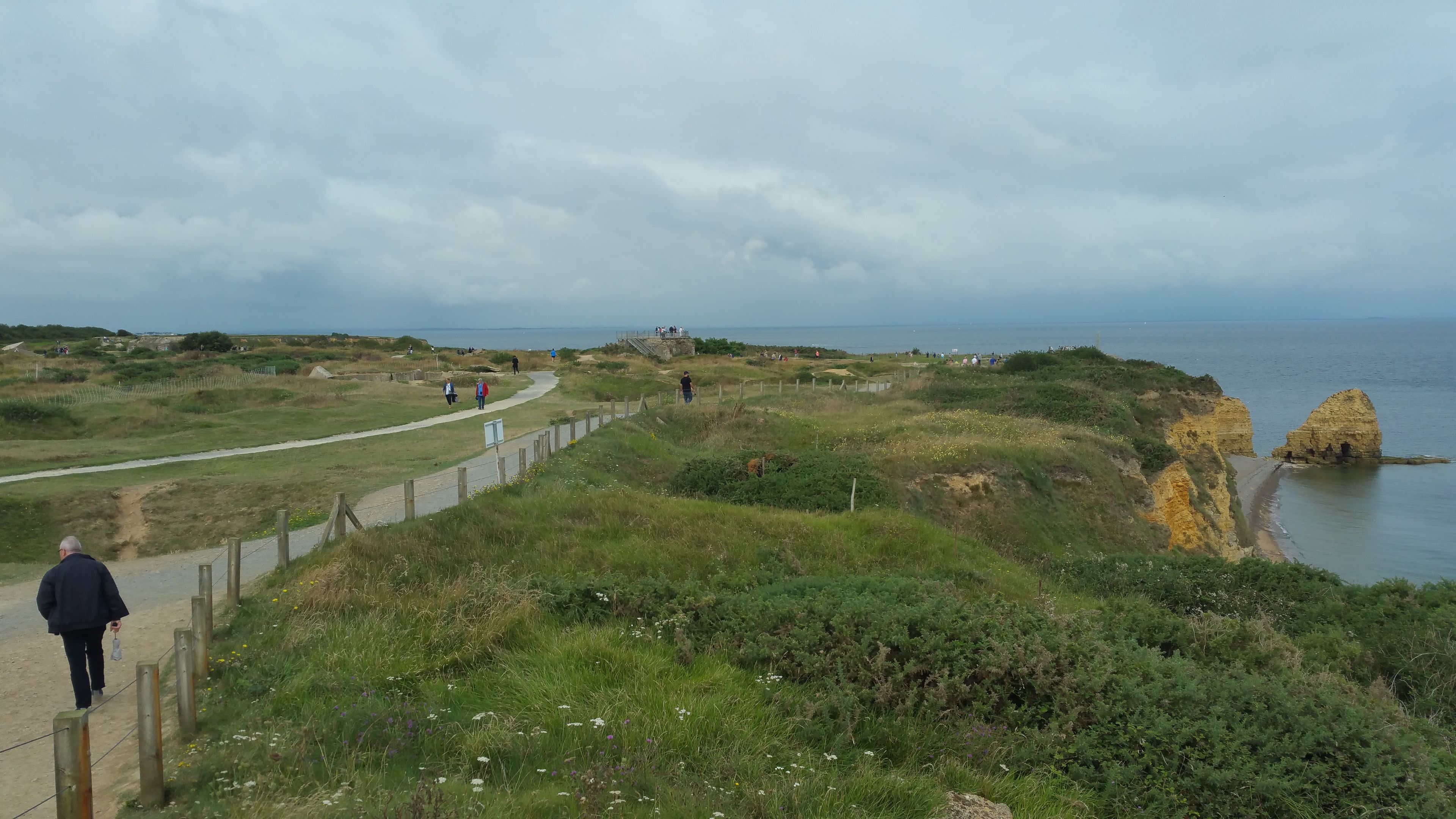 Ein Küstenpfad mit einem Felsen und Blick auf das Meer.