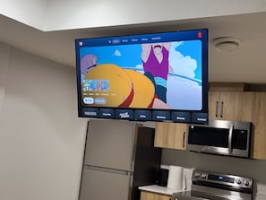 Ein Flachbildfernseher an der Wand über einer Küchenarbeitsplatte mit Mikrowelle und Backofen darunter.