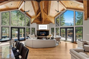 Un salón amplio con chimenea, ventanas grandes y un techo alto con vigas de madera.