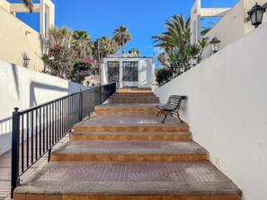 A set of outdoor stairs leading to a covered area with a bench at the bottom. - GuestReady - Los Alisios Corralejo 39 (La Oliva)
