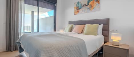 Une chambre à coucher moderne avec un grand lit, une table de chevet, une lampe et un tableau au mur.
