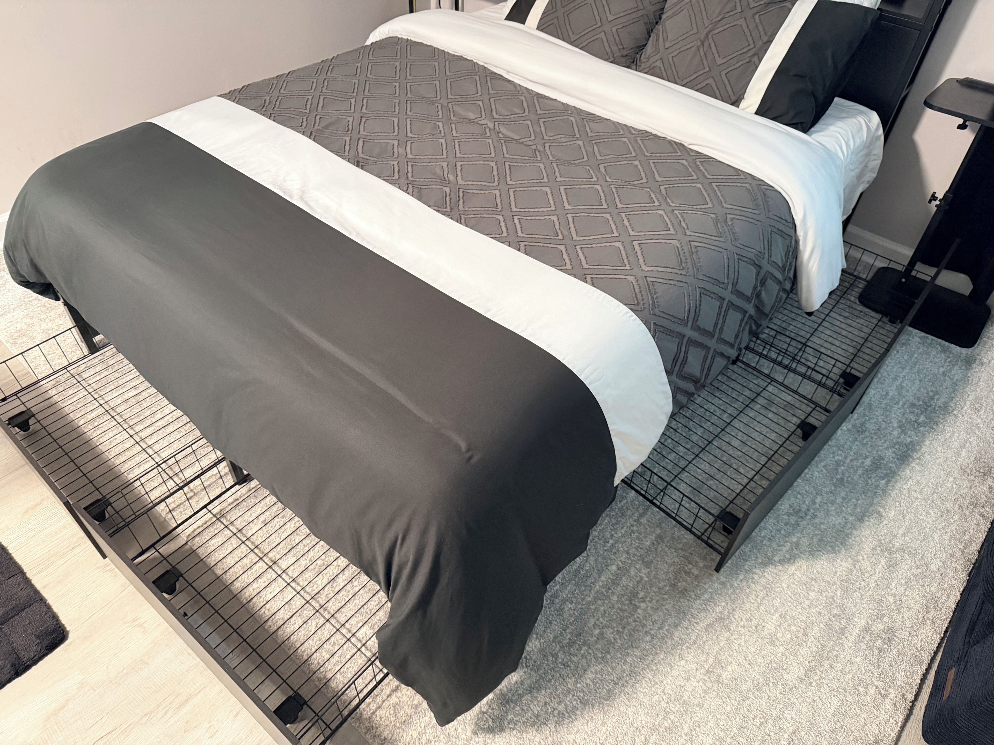 A bed with a patterned bedspread and a black and white blanket.