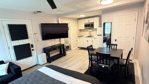 A compact hotel room with a bed, a desk, a chair, a television, and a kitchenette. - Private Studio Suite in Woodbridge, VA Near I-95 & VRE (Woodbridge)