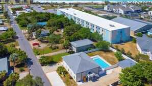 A residential area with a large building, a swimming pool, and a beach in the background. - 1/2 Block to the Beach, West End | Balcony+Pool (Panama City Beach)