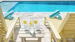 A poolside area with lounge chairs, a table with drinks, and a clear view of the pool. - 1/2 Block to the Beach, West End | Balcony+Pool (Panama City Beach)