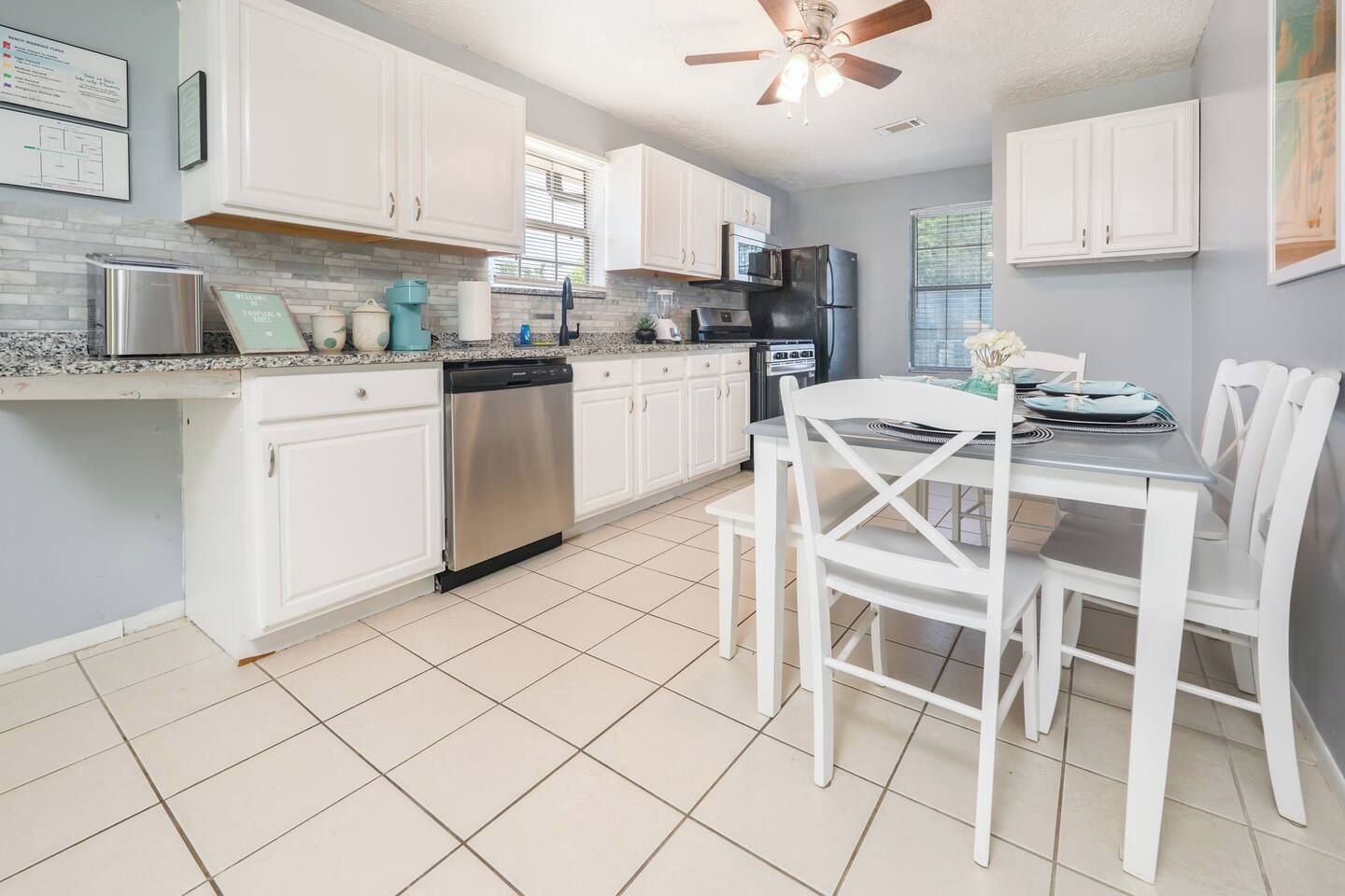 A kitchen with white cabinets, a dishwasher, a microwave, and a dining table with chairs.