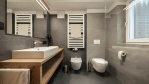 Un baño moderno con un espejo grande, un lavabo, un bidé y un inodoro.