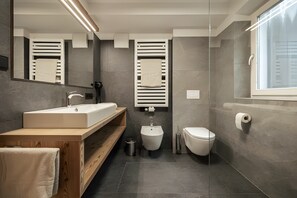 Un bagno moderno con uno specchio grande, un lavandino, un bidet e un water.