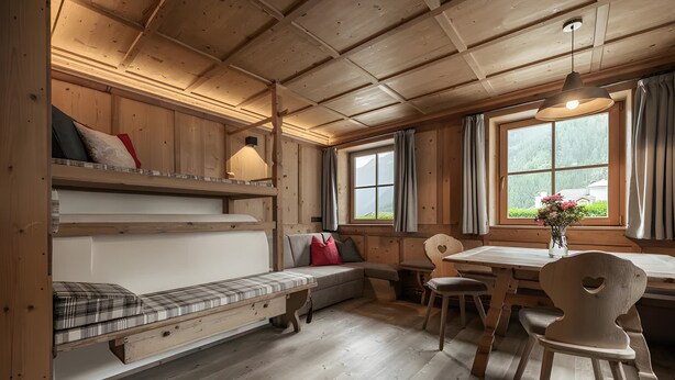 Interior acogedor de una cabaña con cama en el altillo, una mesa de comedor y un banco.