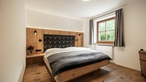 Un dormitorio con cabecera de madera, una ventana con cortinas y suelo de madera.