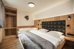 A bedroom with a bed, a wooden wardrobe, and a wall-mounted light fixture.