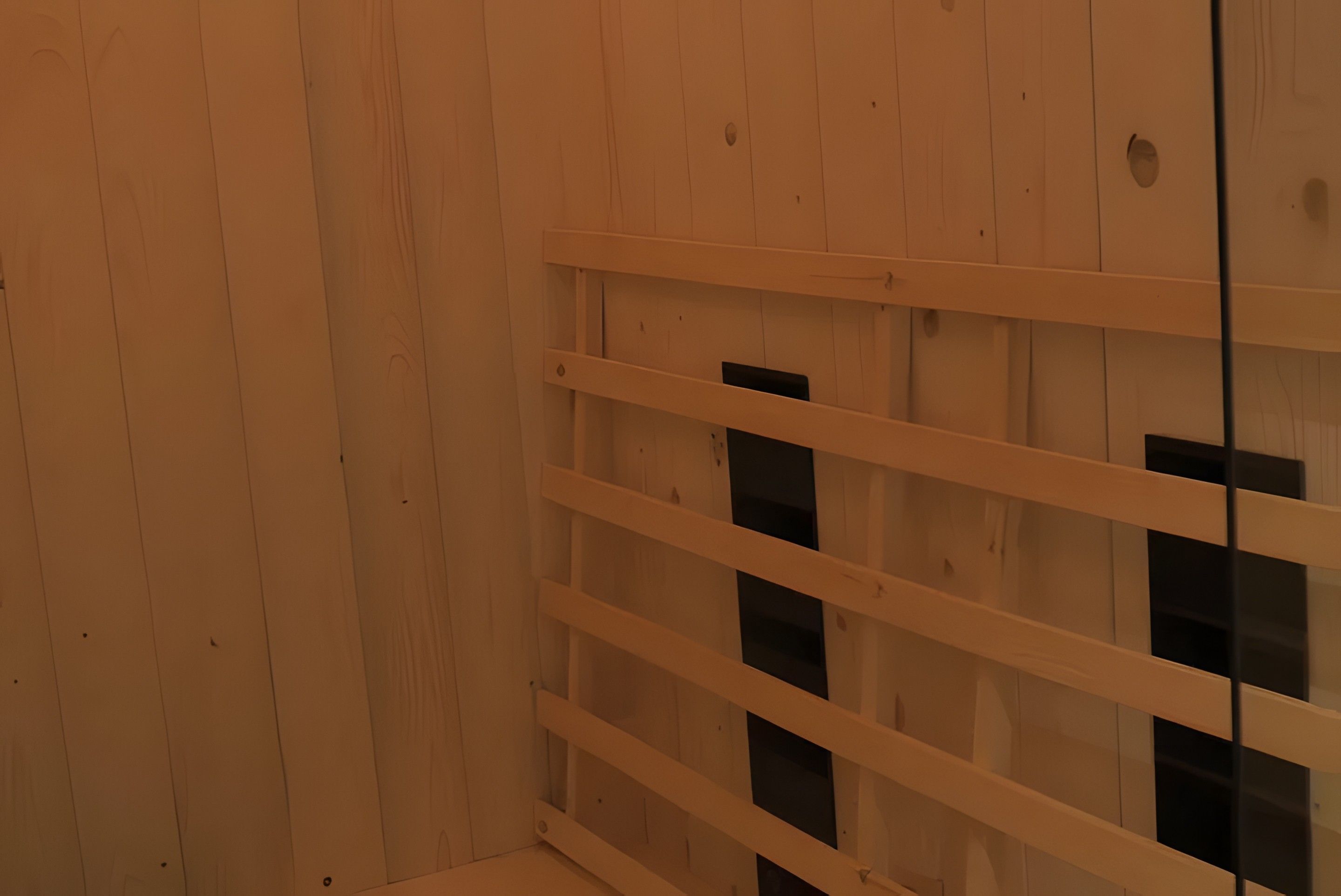 Habitació amb parets de fusta i sostre blanc. Hi ha un moble blanc amb diversos calaixos.