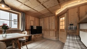 Un interior de madera con una mesa de comedor, sillas, un televisor y un sofá.