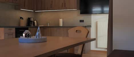 A modern kitchen with wooden cabinets, a flat-screen TV, and a dining area with a table and chairs.