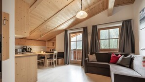 Interior acogedor de una cabaña con cocina, comedor y zona de estar con sofá y cortinas.