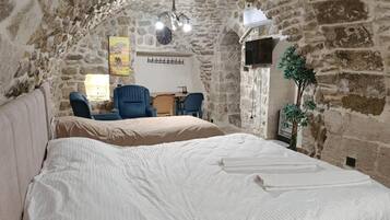 A stone-walled room with a bed, a chair, and a table.