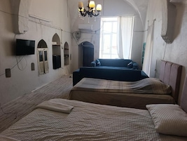 Una habitación con dos camas, televisión y un candelabro.