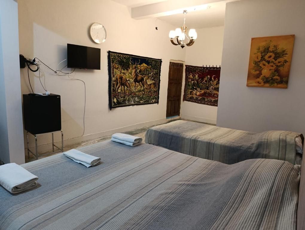 Habitación de hotel con dos camas, un televisor de pantalla plana, obras de arte en las paredes y un candelabro.
