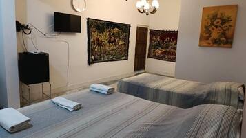 Habitación de hotel con dos camas, un televisor de pantalla plana, obras de arte en las paredes y un candelabro.