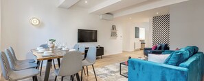 Ein modernes Wohnzimmer mit Essbereich, einem an der Wand befestigten Flachbildfernseher und einer Wand mit Streifenmuster.