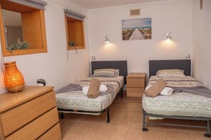 Ein Schlafzimmer mit zwei Betten, einer Holzkommode, einem Spiegel, einer Wandlampe und einem Bild.
